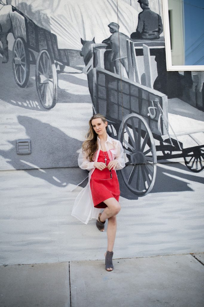 blonde woman, red dress, black and white mural, sheer jacket 