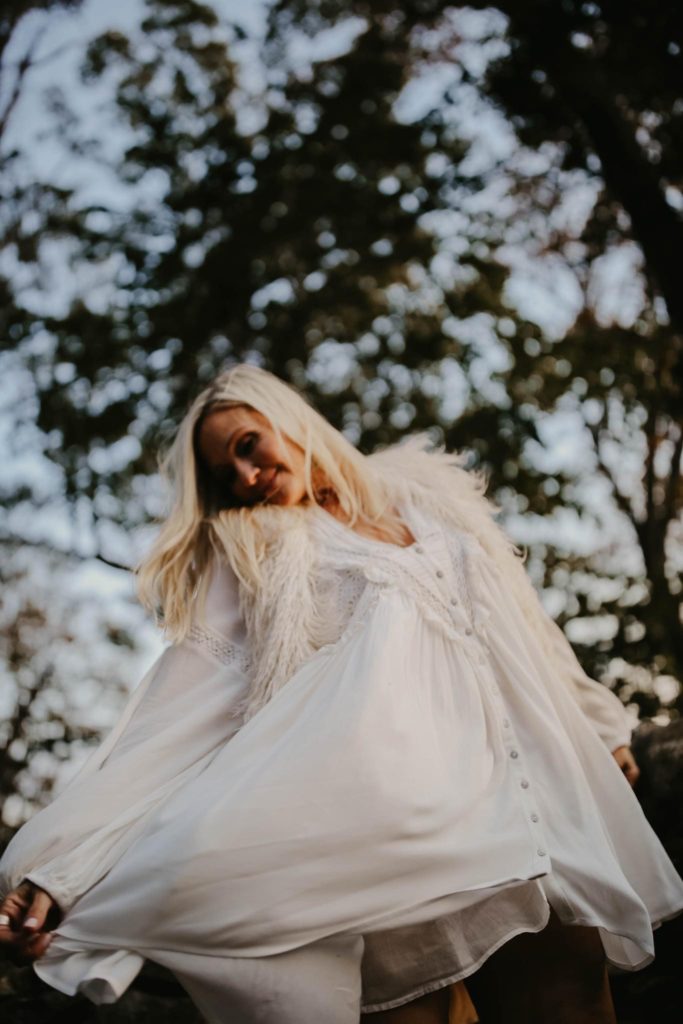 woman white dress fur vest dancing in nature for photo shoot