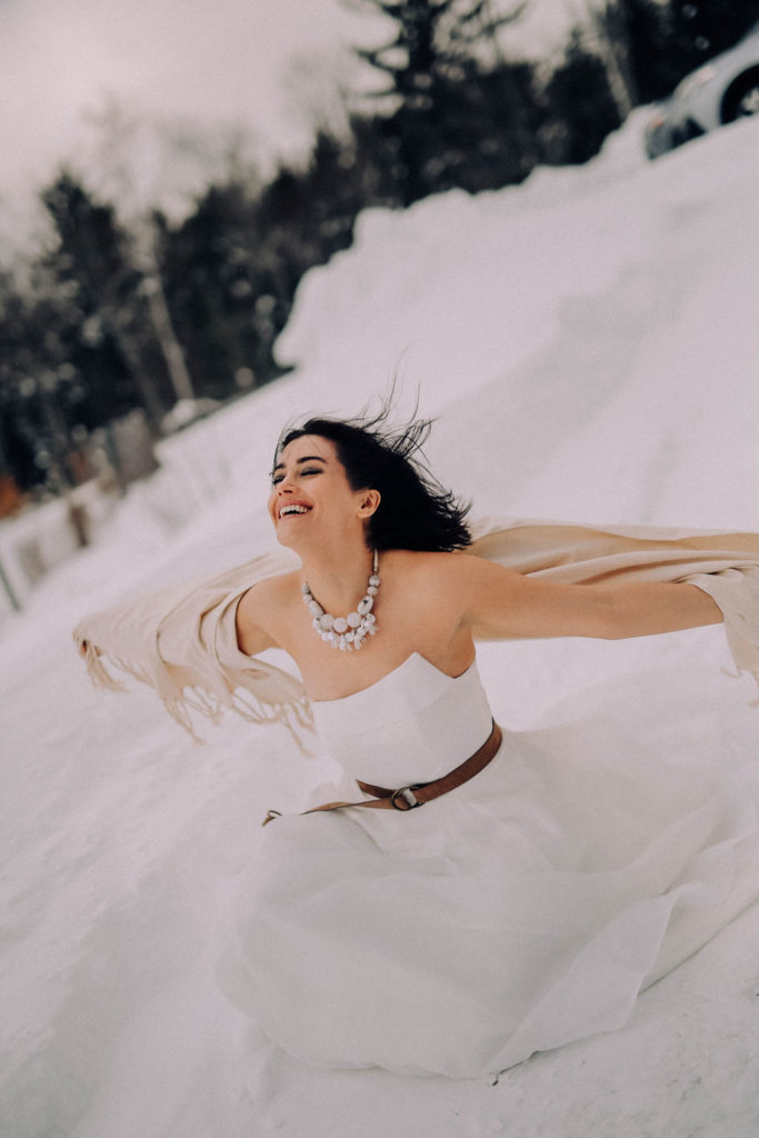 woman in the snow being blown by the wind in a white dress