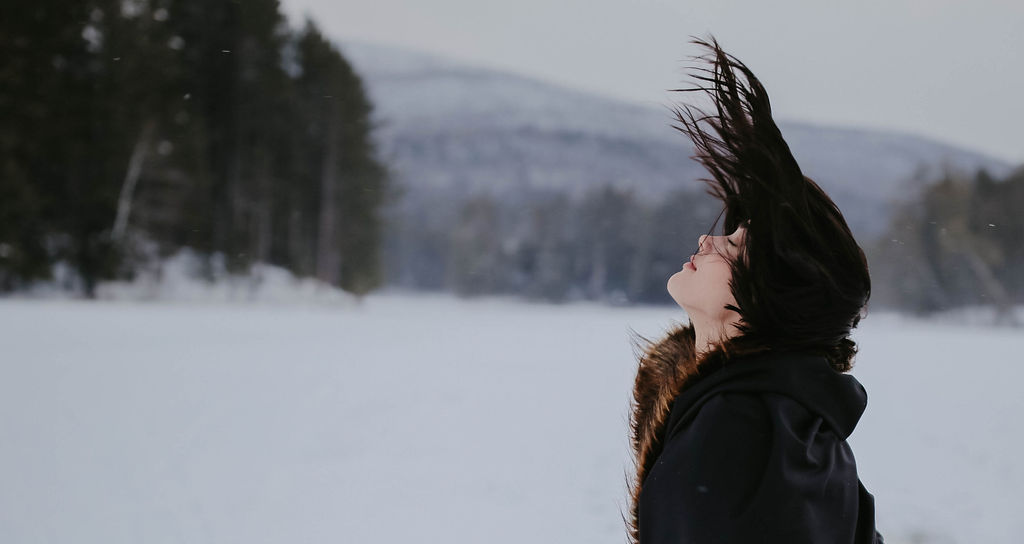 woman flipping her hair in the mountains wearing a fur cloak 