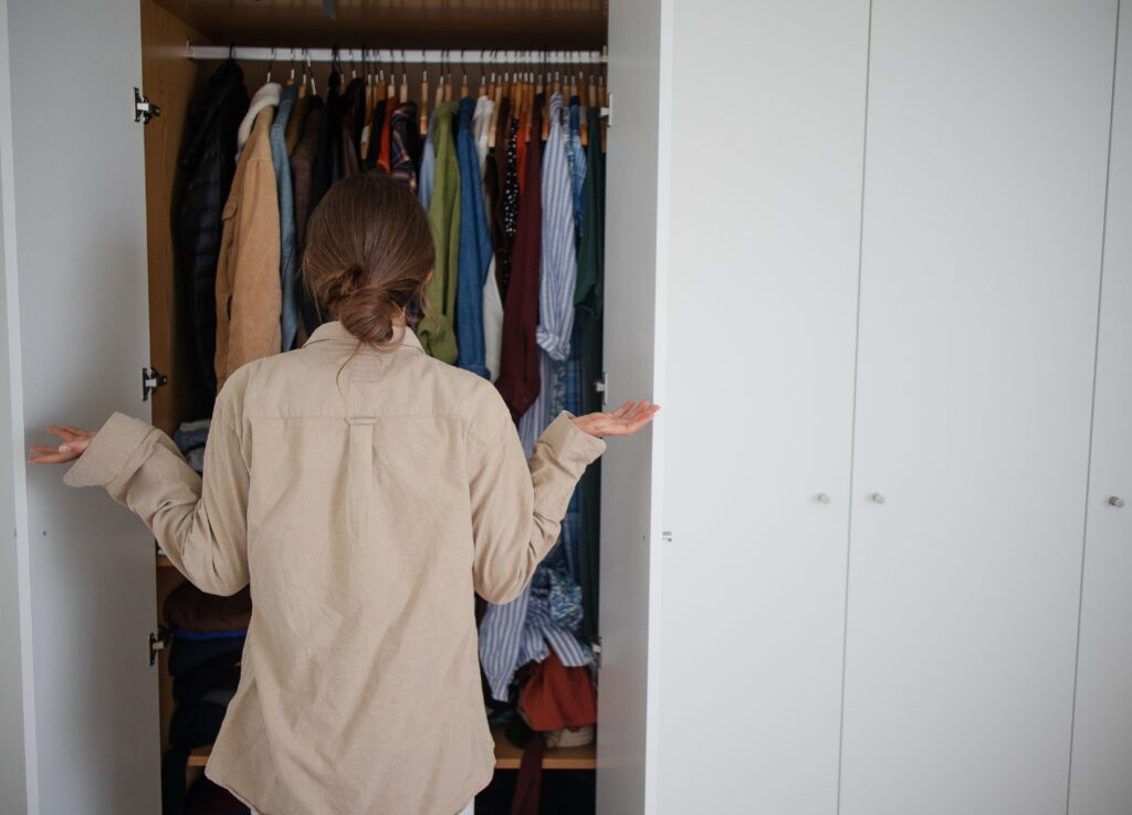woman looking at her closet and not knowing what to wear, experiencing wardrobe fatigue